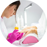 Woman getting her nails painted at a nail salon by a nail tech.